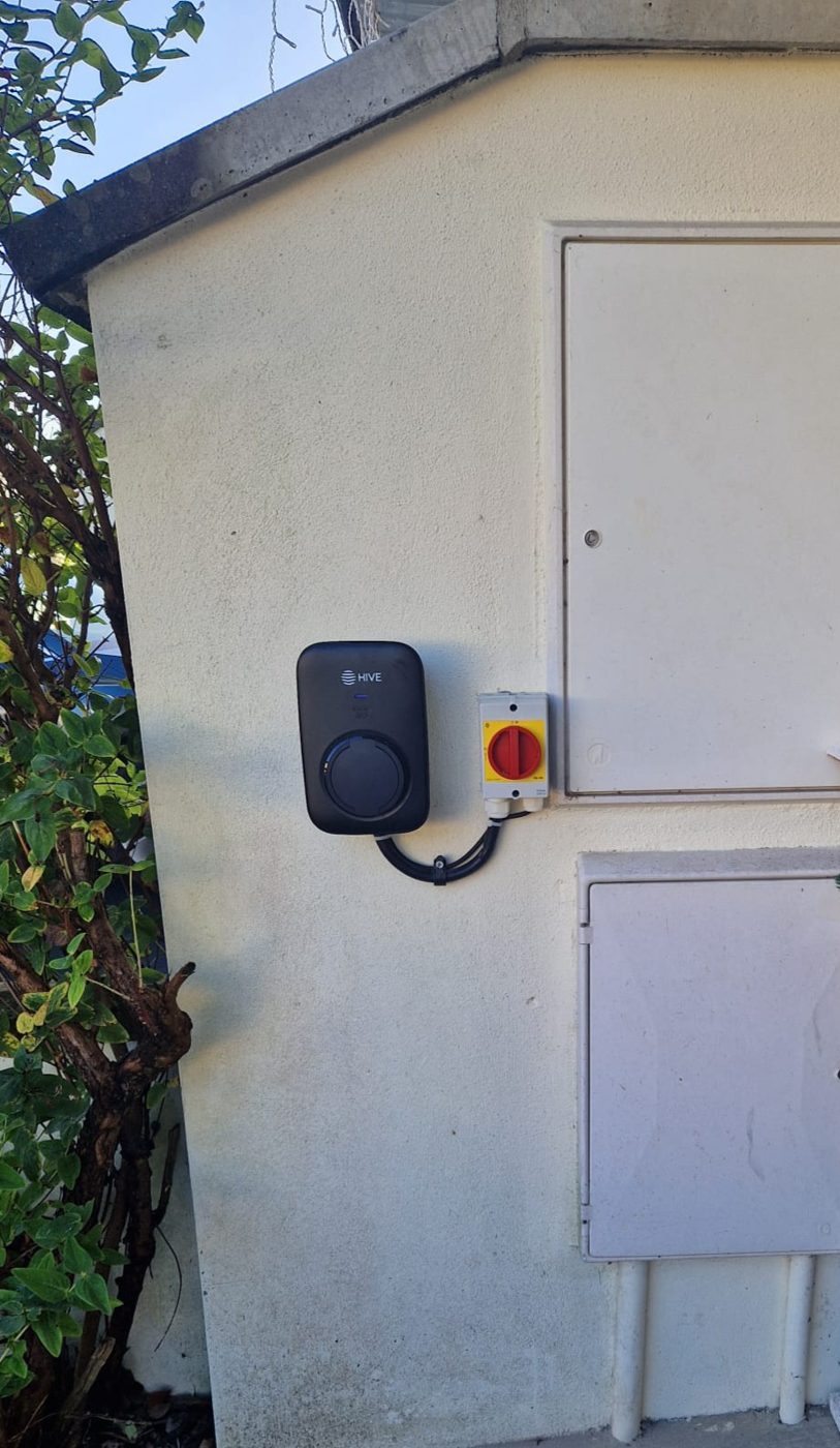 A Hive EV charger and isolator on the gable of a rendered outbuilding