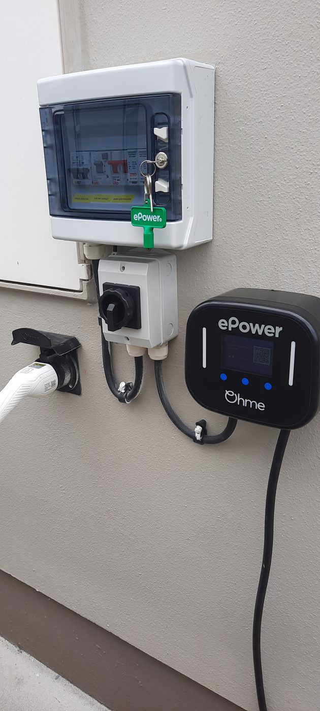 An ePower EV charger fitted below a small consumer unit and isolator on a cream wall