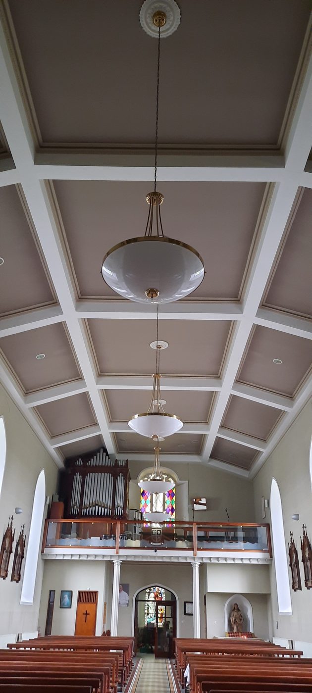 A church interior with pendant lights hanging along the nave