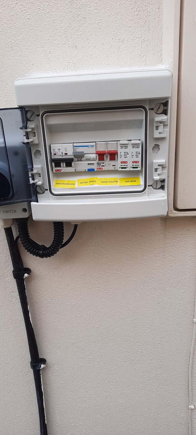 An outdoor distribution board with breakers, its cable run neatly down a cream wall